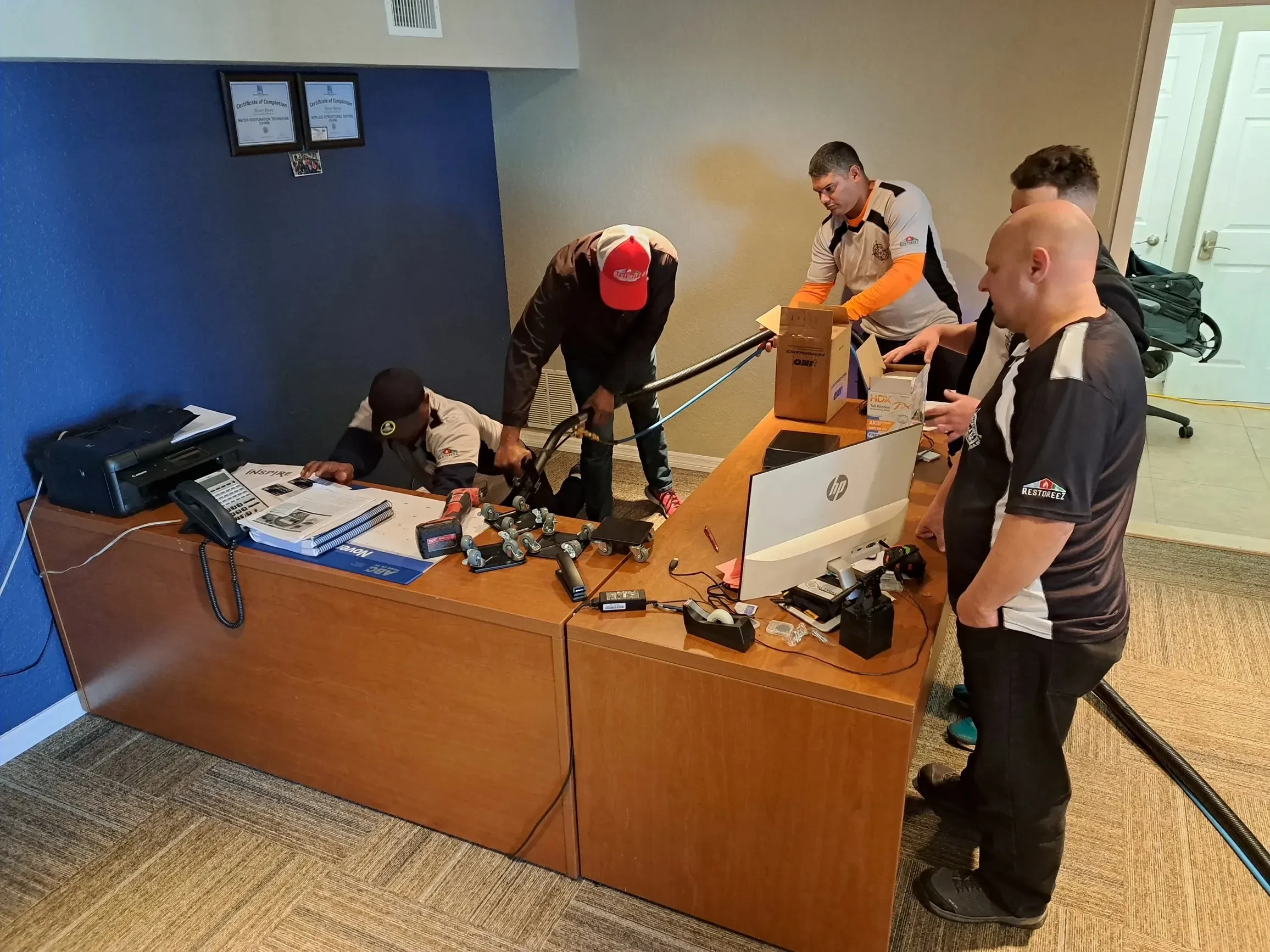 Five people working together at a desk in an office.